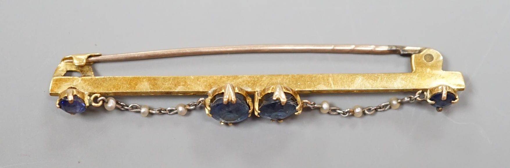 An early 20th century yellow metal sapphire and seed pearl set bar brooch, 61mm, gross weight 5.6 grams.